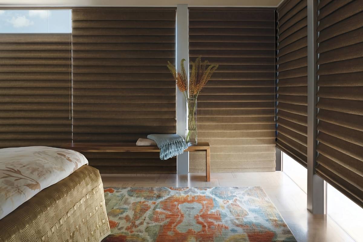 Partially open Hunter Douglas Vignette® Roman Shades as blackout shades in a cozy, neutral bedroom at White House Designs For Life near New Jersey (NJ)