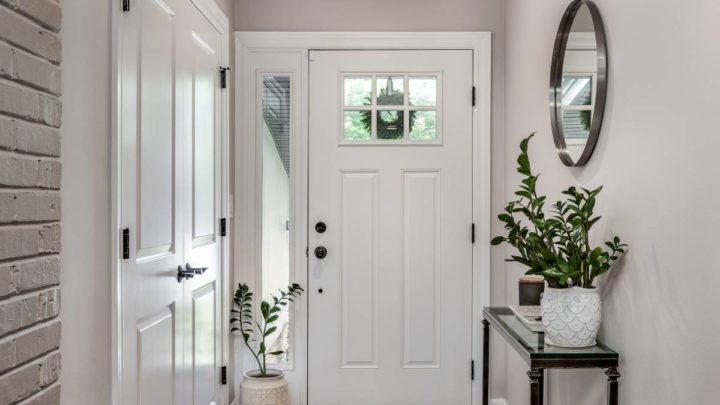 A cozy entryway featuring a front door with sidelights, greenery, and a console table with decor at White House Designs For Life near New Jersey (NJ)