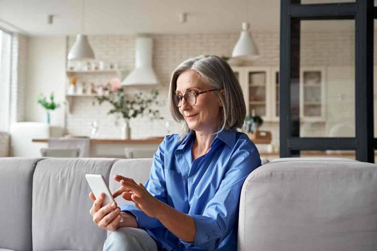 A person controlling their automated blinds with PowerView® Automation from their phone on the couch at White House Designs For Life near New Jersey (NJ)