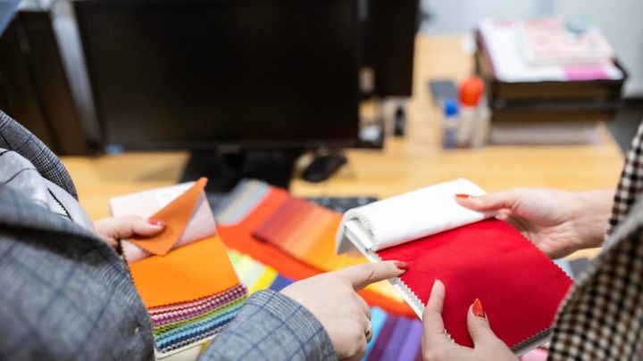 A professional design expert helping an interior designer explore several fabric swatches in a showroom at White House Designs for Life near Paramus, NJ