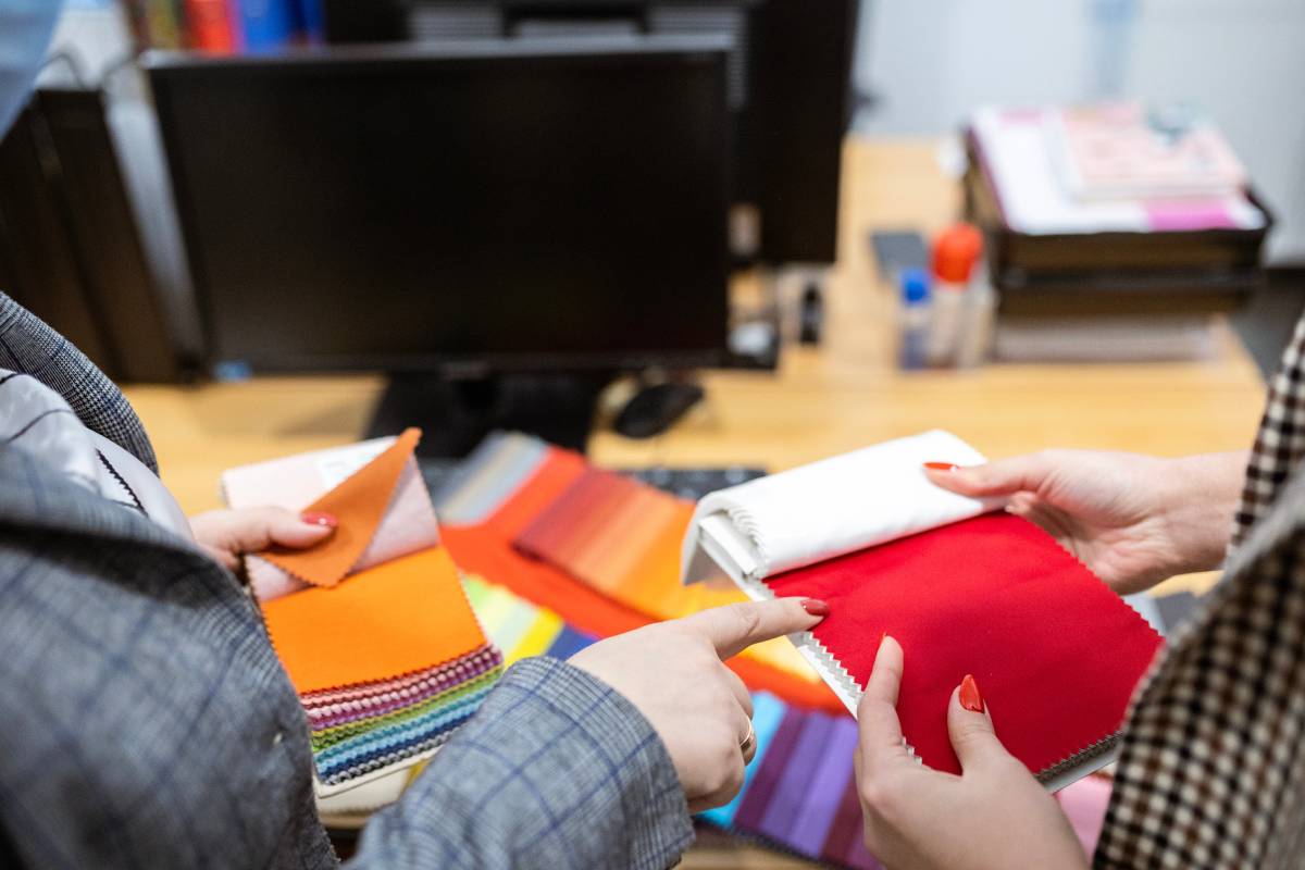 A professional design expert helping an interior designer explore several fabric swatches in a showroom at White House Designs for Life near Paramus, NJ