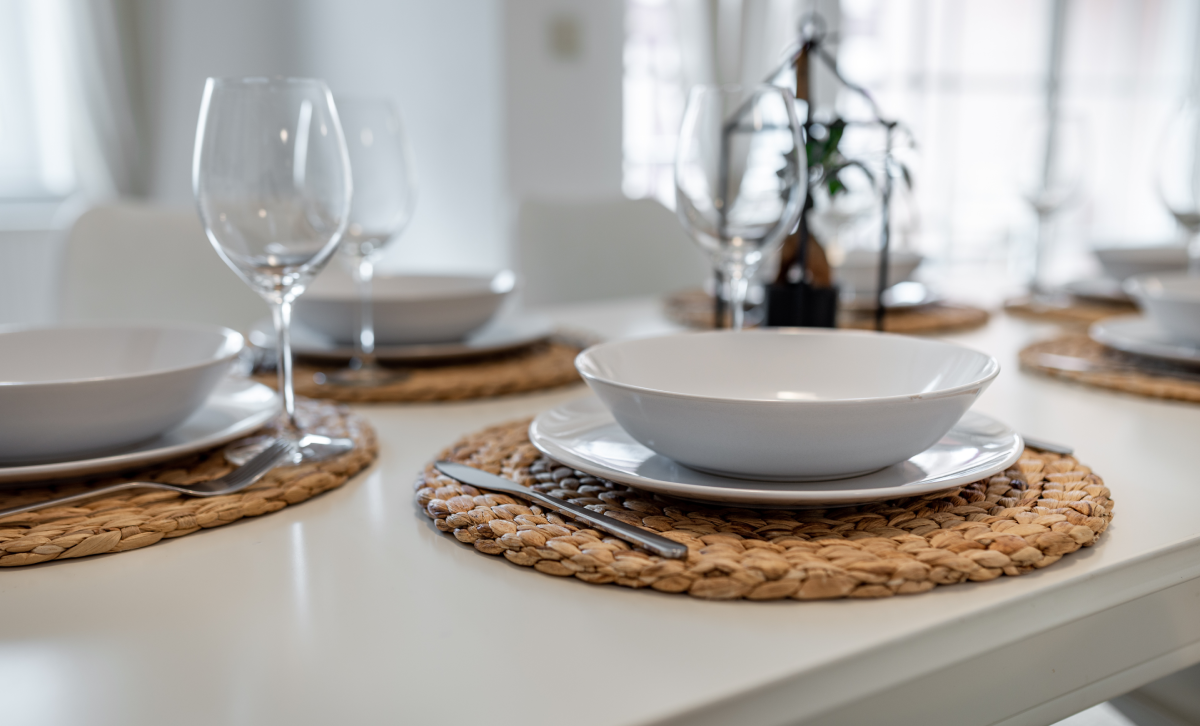Image of a small dining room with a set table with white dinnerware and wine glasses