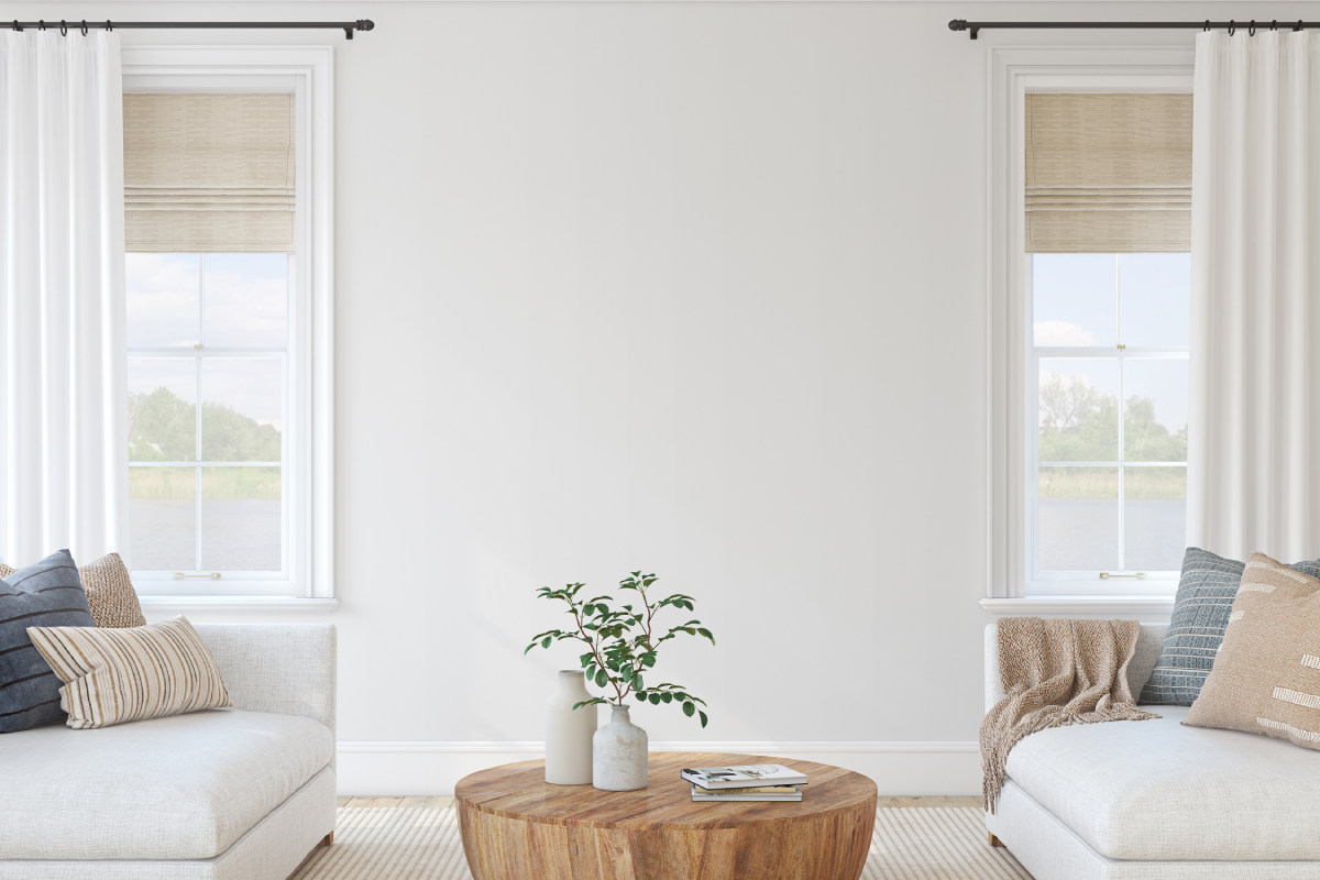 A bright and airy living room with Roman shades paired with drapes on two windows